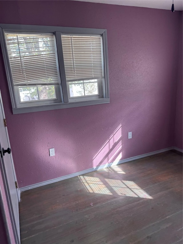 spare room with dark wood-type flooring and a healthy amount of sunlight