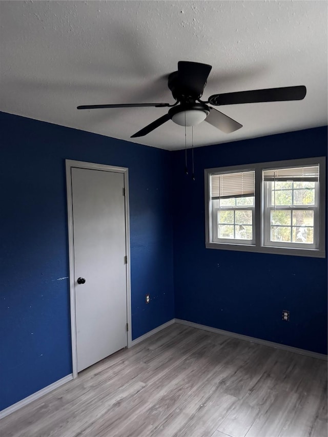 spare room with a textured ceiling, ceiling fan, and light hardwood / wood-style floors