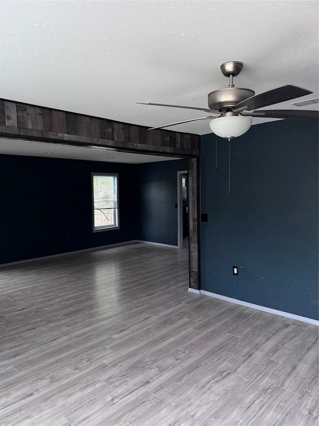 empty room featuring light hardwood / wood-style floors, ceiling fan, and a textured ceiling