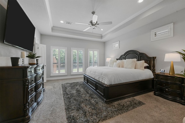 carpeted bedroom with a tray ceiling, ornamental molding, and ceiling fan