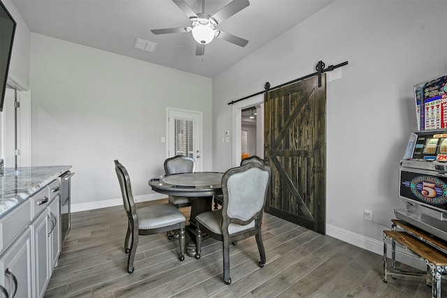 dining room featuring hardwood / wood-style flooring, a barn door, and ceiling fan