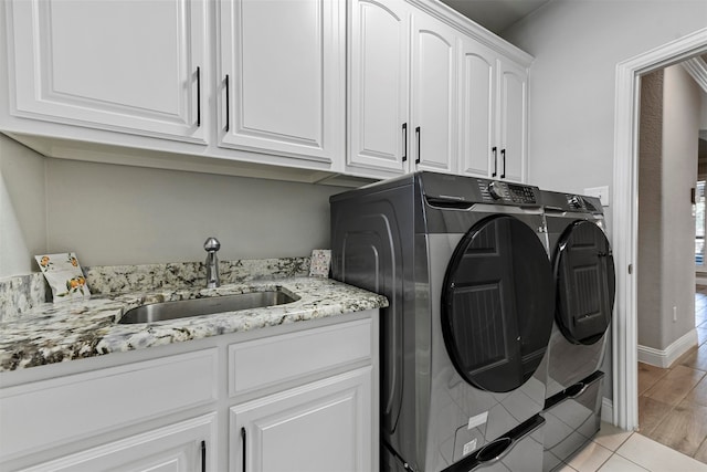 laundry area featuring separate washer and dryer, sink, cabinets, and light hardwood / wood-style flooring