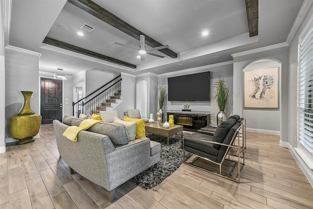 living room with a tray ceiling, ceiling fan, light hardwood / wood-style floors, and ornamental molding