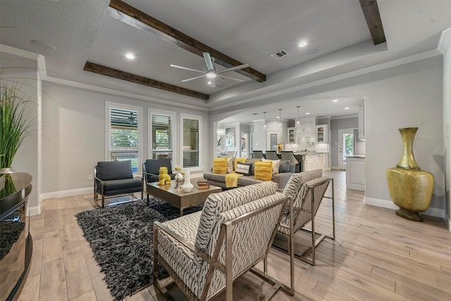 living room with beamed ceiling, ceiling fan, ornamental molding, and light hardwood / wood-style floors