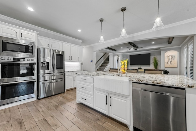 kitchen with ceiling fan, light stone counters, white cabinetry, and appliances with stainless steel finishes