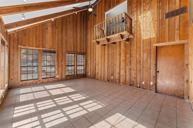 spare room with beam ceiling, wood walls, high vaulted ceiling, and light tile patterned floors