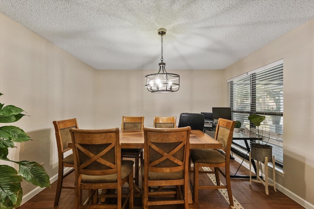dining room with a textured ceiling, baseboards, wood finished floors, and a chandelier