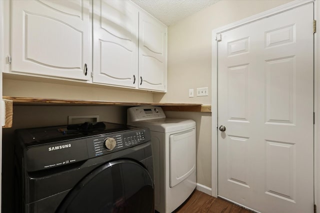 laundry area featuring washing machine and dryer, cabinet space, a textured ceiling, and dark wood-style flooring