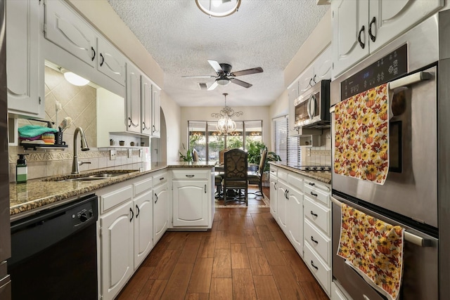 kitchen featuring stainless steel appliances, a sink, a peninsula, white cabinetry, and a textured ceiling