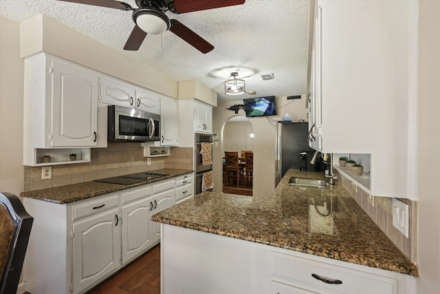 kitchen featuring appliances with stainless steel finishes, a sink, a ceiling fan, backsplash, and white cabinetry