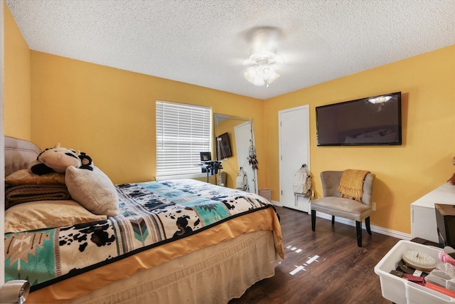 bedroom featuring dark wood-style floors, a textured ceiling, and baseboards