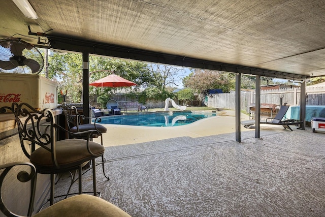 view of pool featuring a water slide, a fenced backyard, and a patio