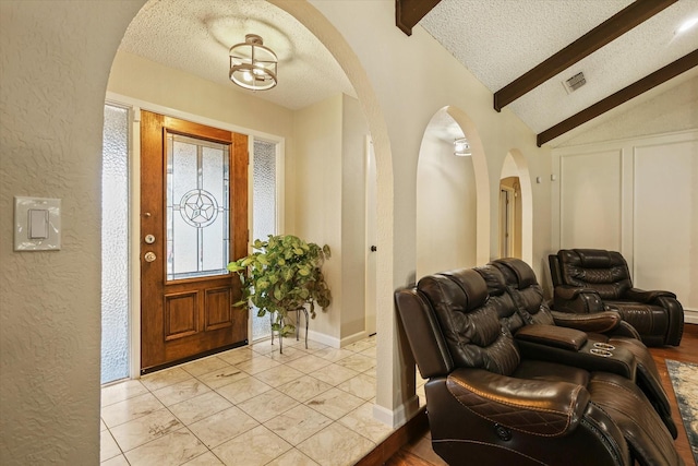 foyer entrance with a textured wall, a textured ceiling, arched walkways, and baseboards