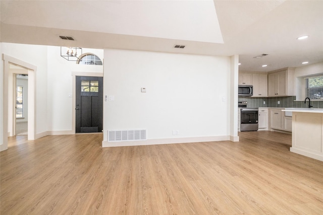 interior space featuring plenty of natural light, an inviting chandelier, and light wood-type flooring