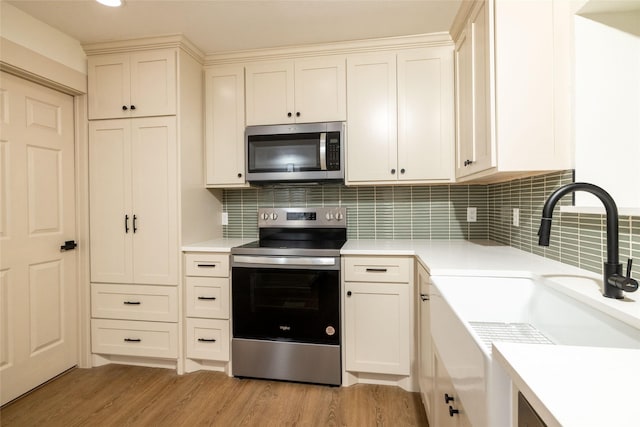 kitchen with decorative backsplash, sink, stainless steel appliances, and light wood-type flooring