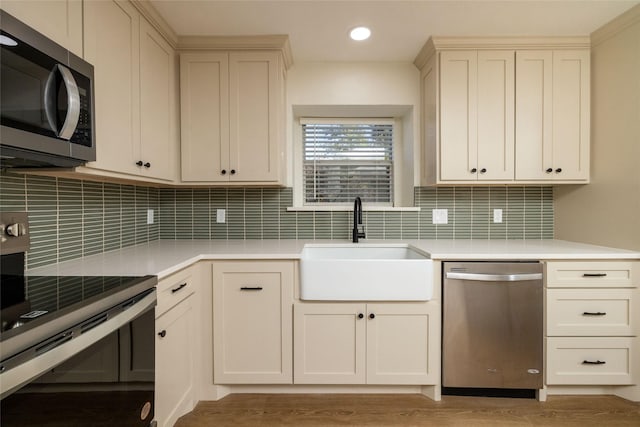 kitchen featuring sink, backsplash, stainless steel appliances, and cream cabinets