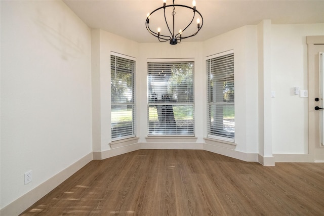 unfurnished dining area featuring hardwood / wood-style flooring and a chandelier