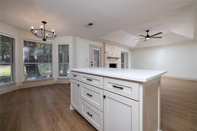 kitchen with decorative light fixtures, white cabinets, dark wood-type flooring, a tray ceiling, and a kitchen island