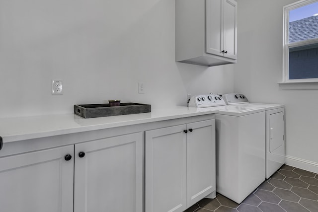 clothes washing area with cabinets, dark tile patterned flooring, and washer and dryer