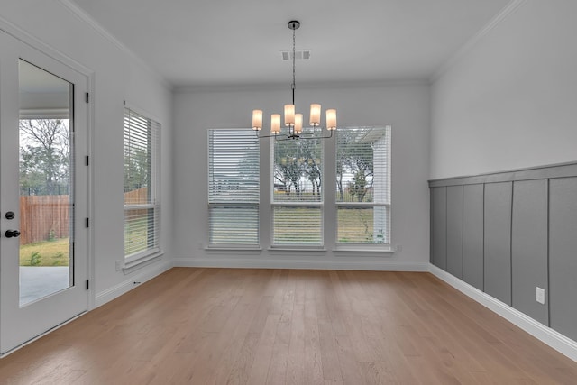 unfurnished dining area featuring light hardwood / wood-style flooring, an inviting chandelier, and ornamental molding