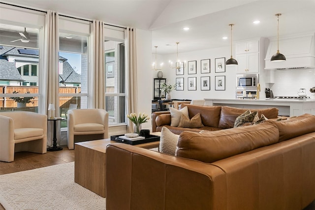 living room featuring lofted ceiling, a chandelier, and light wood-type flooring