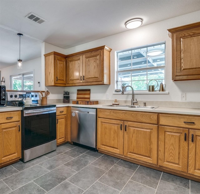 kitchen with a healthy amount of sunlight, appliances with stainless steel finishes, sink, and decorative light fixtures