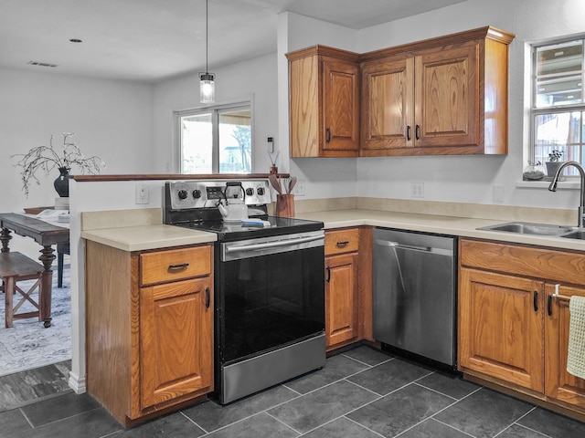 kitchen featuring stainless steel appliances, hanging light fixtures, sink, and dark tile patterned floors