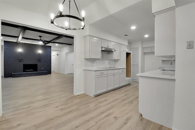 kitchen featuring sink, light hardwood / wood-style flooring, white cabinetry, hanging light fixtures, and decorative backsplash