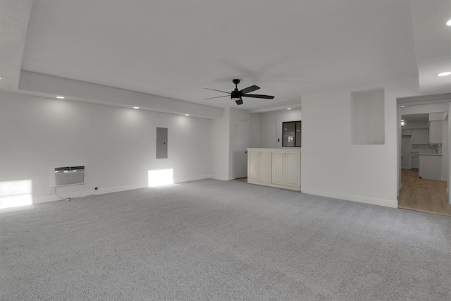 unfurnished living room featuring light colored carpet, an AC wall unit, ceiling fan, and electric panel