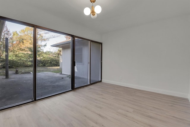 empty room featuring light hardwood / wood-style flooring and a chandelier