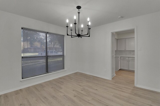 unfurnished dining area featuring a notable chandelier and light hardwood / wood-style flooring