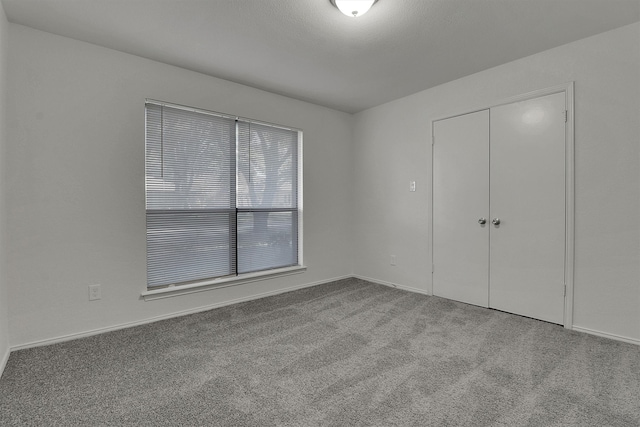 unfurnished bedroom with light colored carpet and a closet