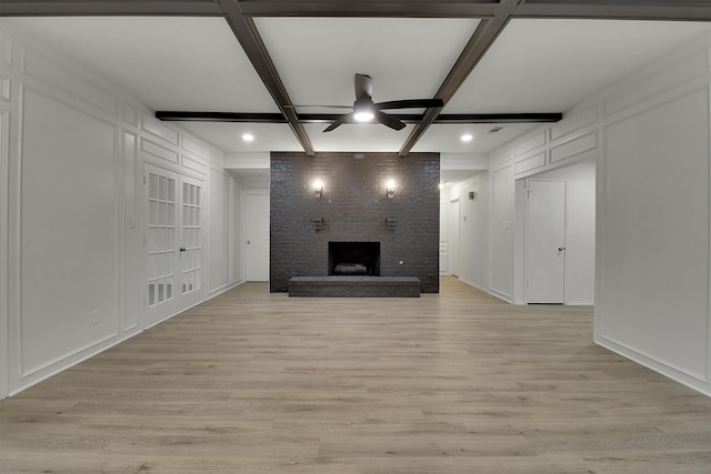 unfurnished living room featuring coffered ceiling, a fireplace, ceiling fan, and light hardwood / wood-style flooring