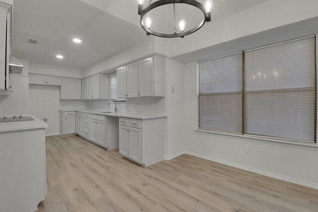 kitchen featuring white cabinetry, decorative backsplash, a notable chandelier, black electric cooktop, and light hardwood / wood-style flooring