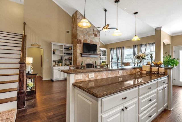 kitchen featuring white cabinets, dark hardwood / wood-style flooring, a fireplace, and high vaulted ceiling