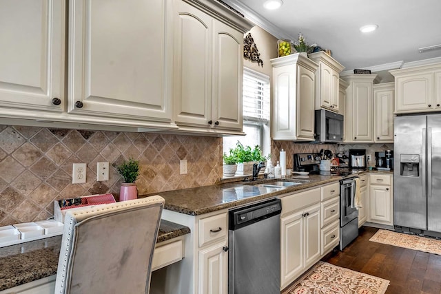 kitchen with ornamental molding, dark stone counters, stainless steel appliances, dark wood-type flooring, and sink