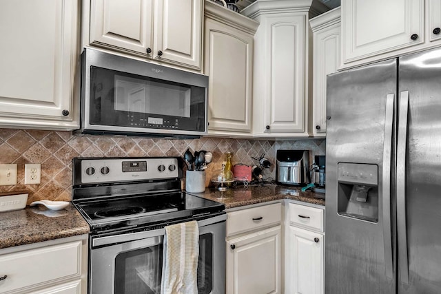 kitchen with stainless steel appliances, tasteful backsplash, white cabinets, and dark stone counters