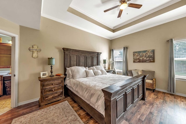 bedroom featuring dark wood-type flooring, crown molding, a raised ceiling, and multiple windows