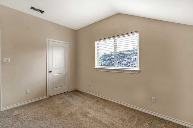 spare room featuring light colored carpet and lofted ceiling