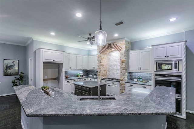 kitchen with appliances with stainless steel finishes, tasteful backsplash, white cabinetry, and a spacious island