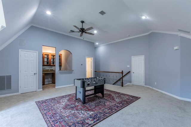 recreation room with ceiling fan, light colored carpet, crown molding, and high vaulted ceiling