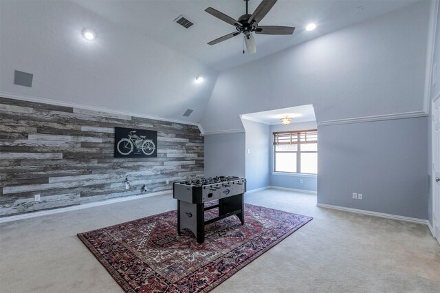 recreation room with ceiling fan, wood walls, crown molding, carpet floors, and vaulted ceiling