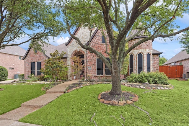 english style home with a front yard and central air condition unit