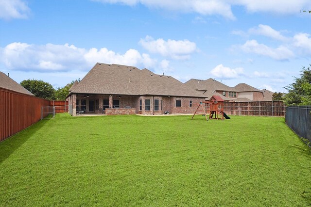 back of property featuring a lawn and a playground