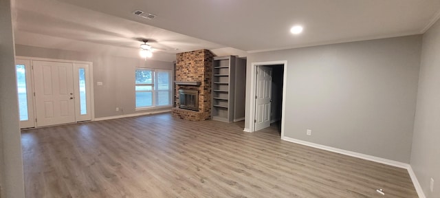 unfurnished living room featuring hardwood / wood-style floors, a brick fireplace, ceiling fan, and ornamental molding