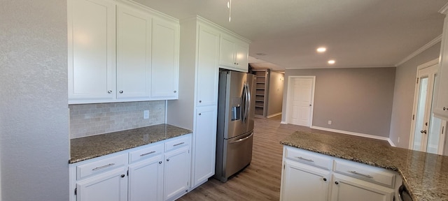 kitchen featuring white cabinetry, stainless steel fridge, dark stone counters, and light hardwood / wood-style floors