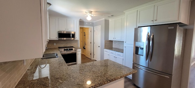 kitchen featuring kitchen peninsula, appliances with stainless steel finishes, decorative backsplash, and white cabinetry