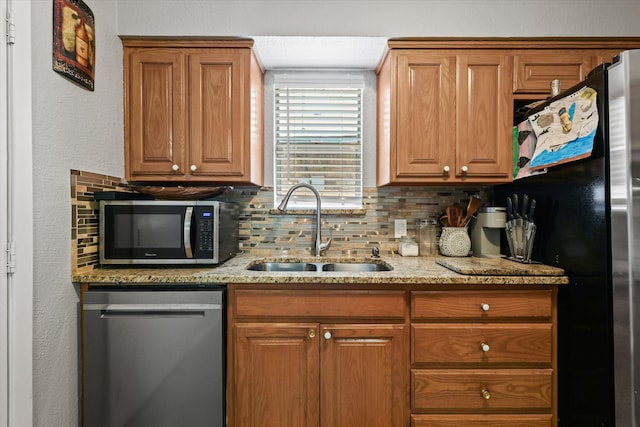 kitchen with backsplash, light stone counters, sink, and stainless steel appliances