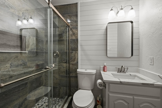 bathroom with vanity, wood walls, an enclosed shower, and toilet