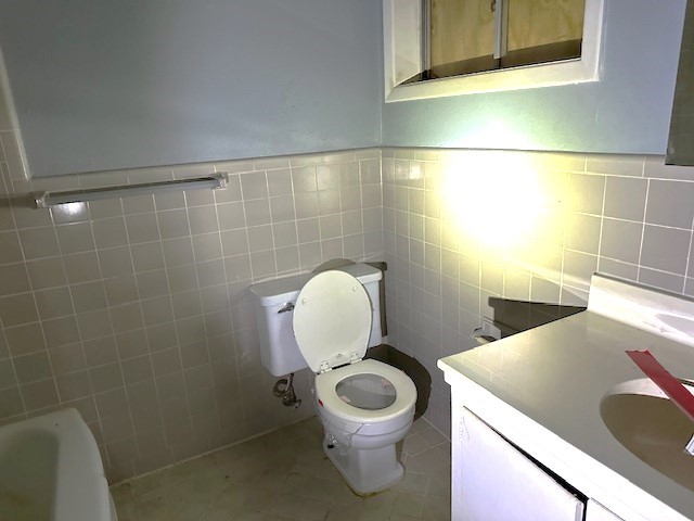 bathroom featuring tile walls, vanity, tile patterned floors, and toilet